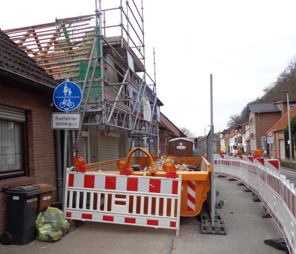 Baustelle an der Straße mit Absperrung, Gerüst und Container